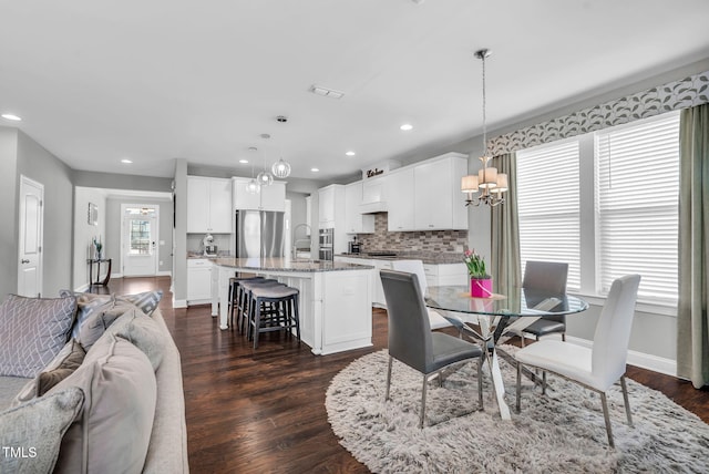 dining room with an inviting chandelier, baseboards, dark wood-type flooring, and recessed lighting