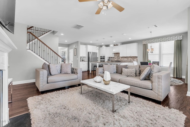 living room with dark wood-type flooring, baseboards, and stairs