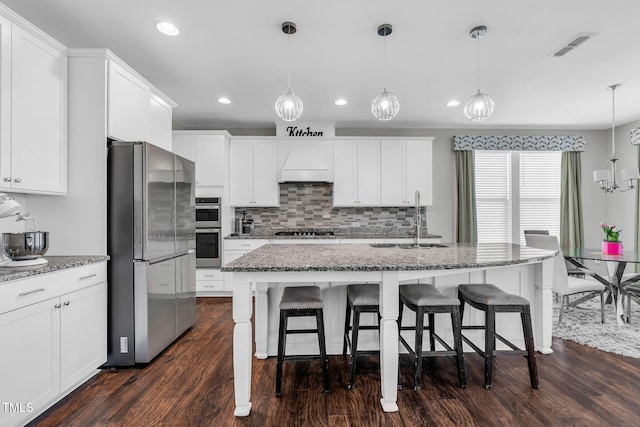 kitchen with white cabinets, custom exhaust hood, stainless steel appliances, and a sink