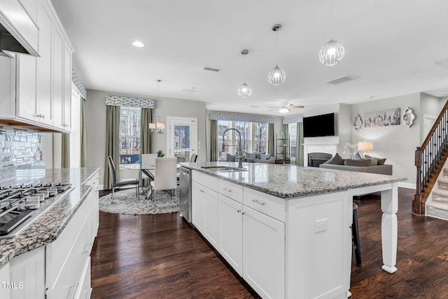 kitchen with stainless steel appliances, dark wood-style flooring, a sink, and light stone counters