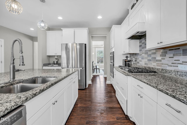 kitchen featuring tasteful backsplash, hanging light fixtures, appliances with stainless steel finishes, white cabinetry, and a sink