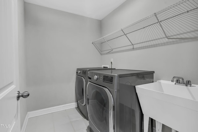 laundry area with a sink, laundry area, baseboards, and washer and dryer