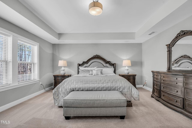 bedroom featuring baseboards, a raised ceiling, and light colored carpet