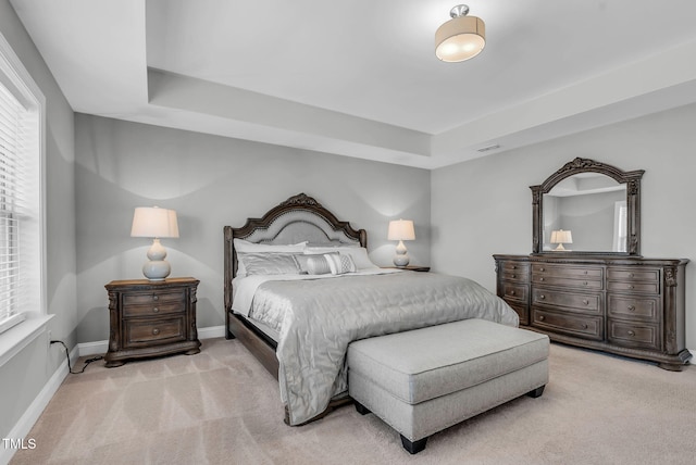 carpeted bedroom with visible vents, baseboards, and a tray ceiling