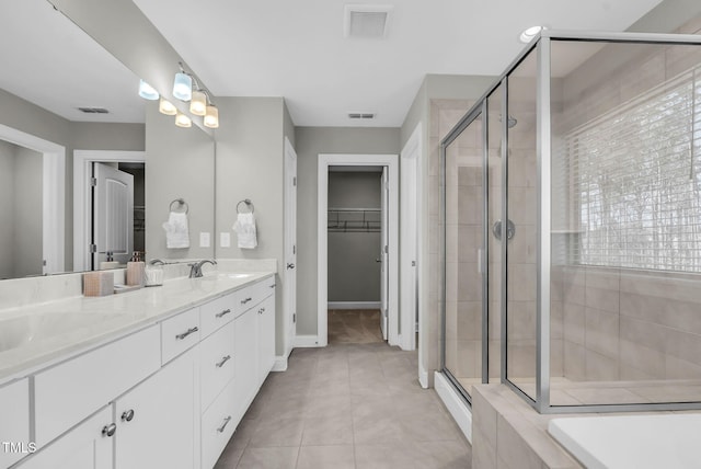 bathroom with a stall shower, visible vents, tile patterned floors, a walk in closet, and a sink