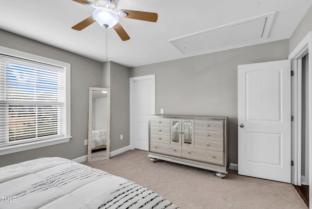 carpeted bedroom featuring ceiling fan, attic access, and baseboards