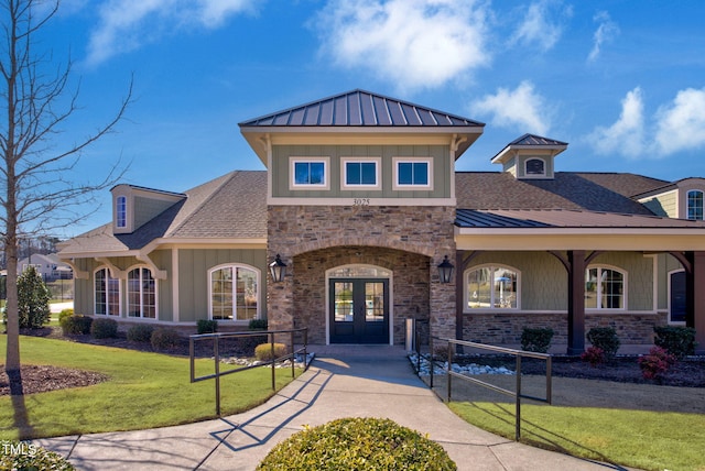 view of front facade with metal roof, a shingled roof, french doors, a front lawn, and a standing seam roof