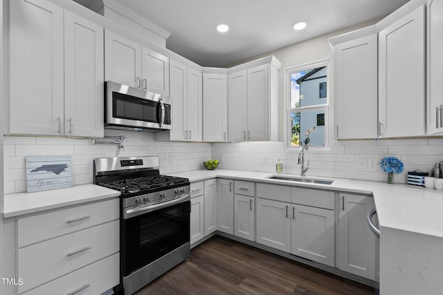 kitchen featuring sink, appliances with stainless steel finishes, white cabinetry, dark hardwood / wood-style flooring, and decorative backsplash