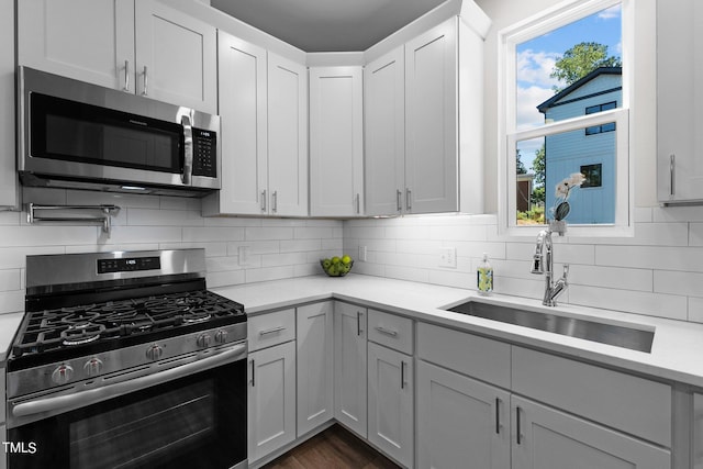 kitchen featuring sink, appliances with stainless steel finishes, dark hardwood / wood-style floors, white cabinets, and backsplash