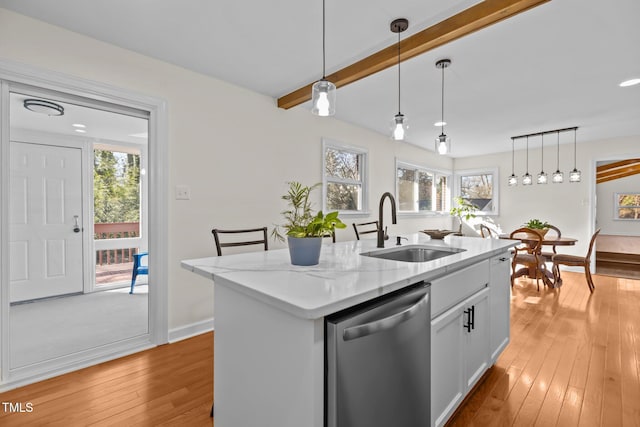 kitchen featuring sink, white cabinetry, stainless steel dishwasher, an island with sink, and light stone countertops