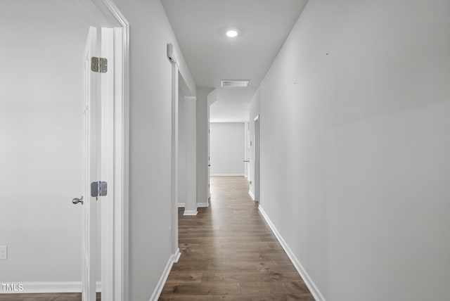 hall featuring visible vents, baseboards, and dark wood finished floors