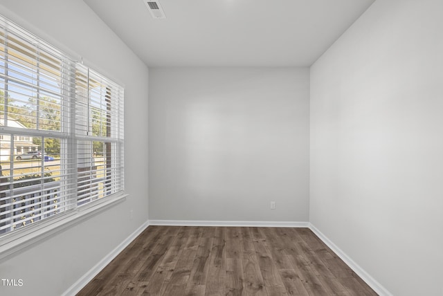 unfurnished room with wood finished floors, baseboards, and visible vents