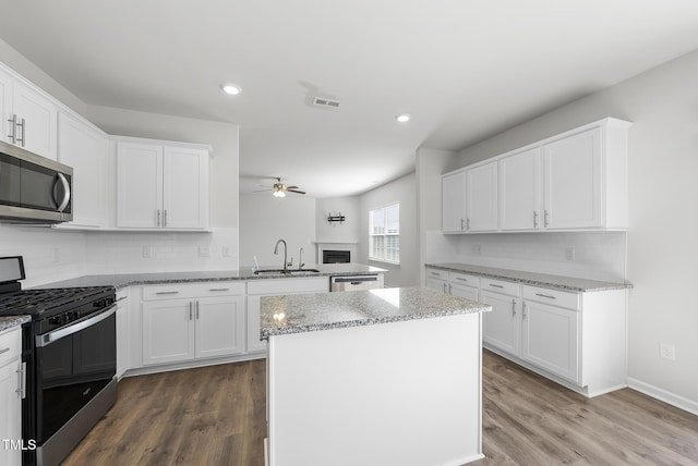 kitchen with visible vents, a ceiling fan, a sink, a kitchen island, and appliances with stainless steel finishes