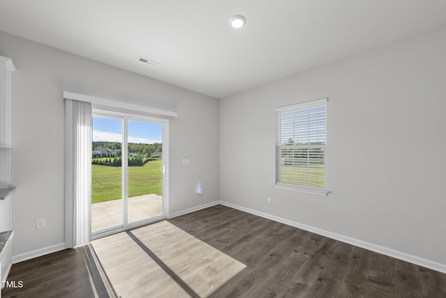 empty room featuring dark wood-type flooring, baseboards, and visible vents