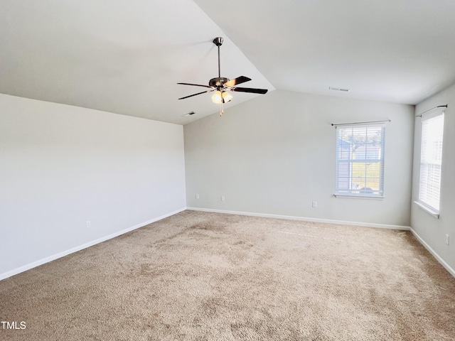 carpeted spare room featuring visible vents, baseboards, a ceiling fan, and vaulted ceiling