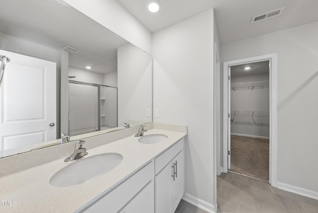 full bathroom with double vanity, visible vents, a stall shower, and a sink