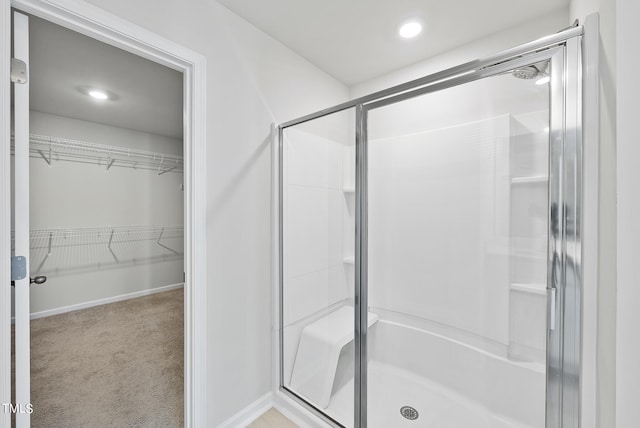 full bath featuring a spacious closet, a shower stall, and baseboards