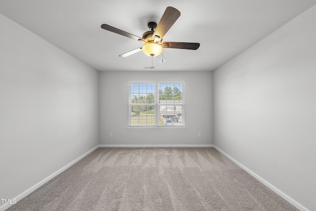 unfurnished room with visible vents, light colored carpet, a ceiling fan, and baseboards