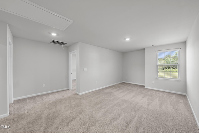 empty room with attic access, carpet, visible vents, and baseboards