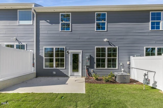 rear view of property featuring central AC unit, a patio area, and a lawn