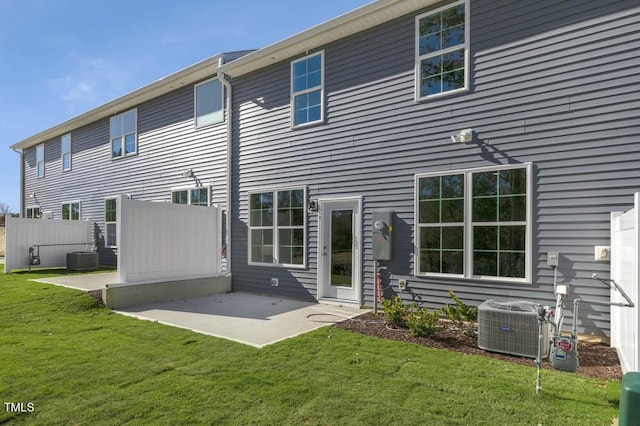 rear view of house with cooling unit, a patio, and a lawn