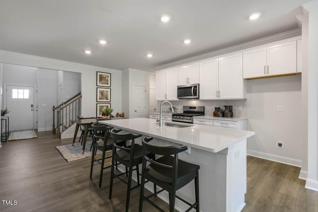 kitchen with stainless steel appliances, white cabinetry, a kitchen island with sink, and sink