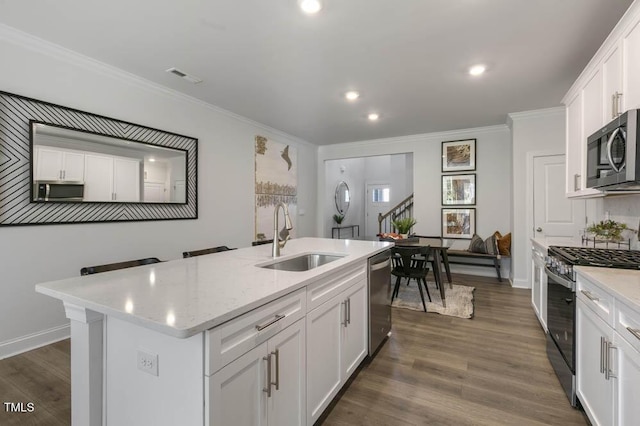 kitchen featuring sink, stainless steel appliances, an island with sink, and white cabinets