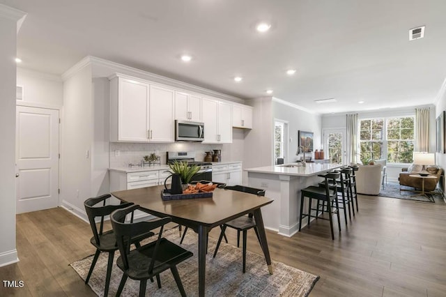 kitchen featuring a center island with sink, a breakfast bar area, white cabinets, and appliances with stainless steel finishes