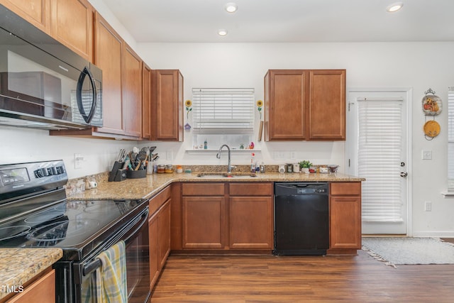 kitchen with dark hardwood / wood-style flooring, light stone countertops, sink, and black appliances