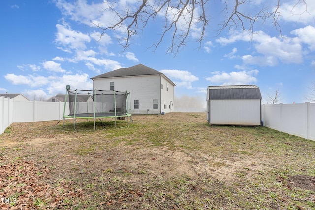 back of property featuring a trampoline, a yard, and a shed