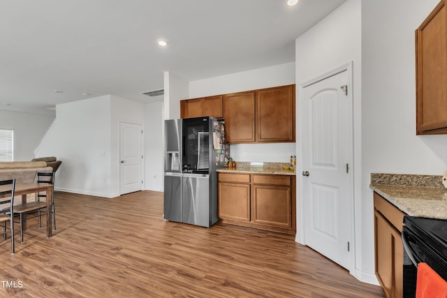 108 Bonnie Girl Ct, Lillington, NC 27546 - kitchen with stainless steel fridge with ice dispenser, brown cabinets, light stone counters, and wood finished floors