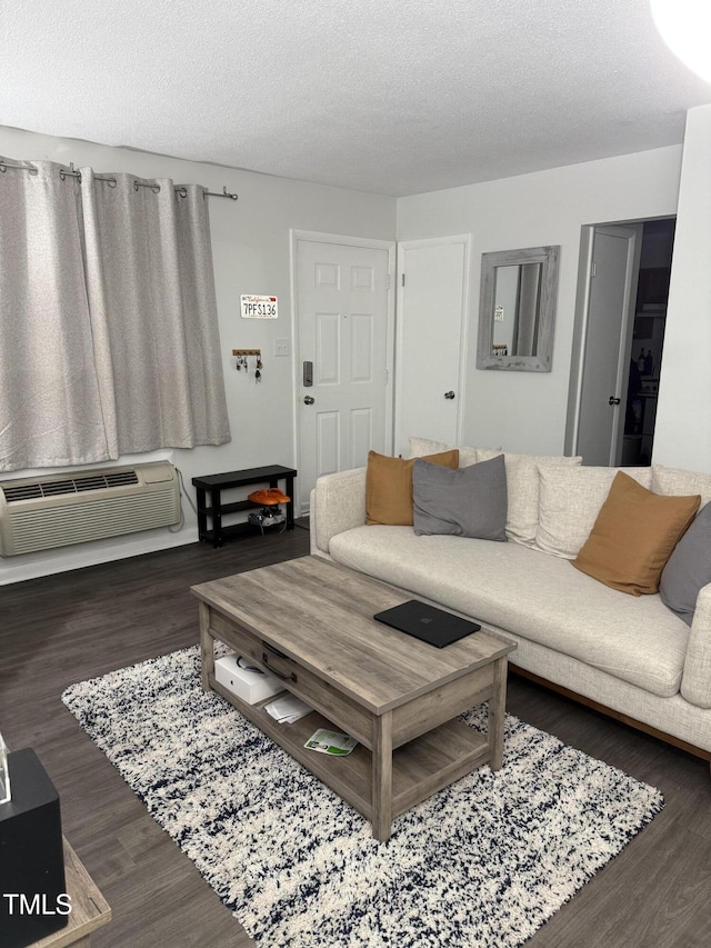 living room featuring dark hardwood / wood-style floors, a textured ceiling, and a wall unit AC