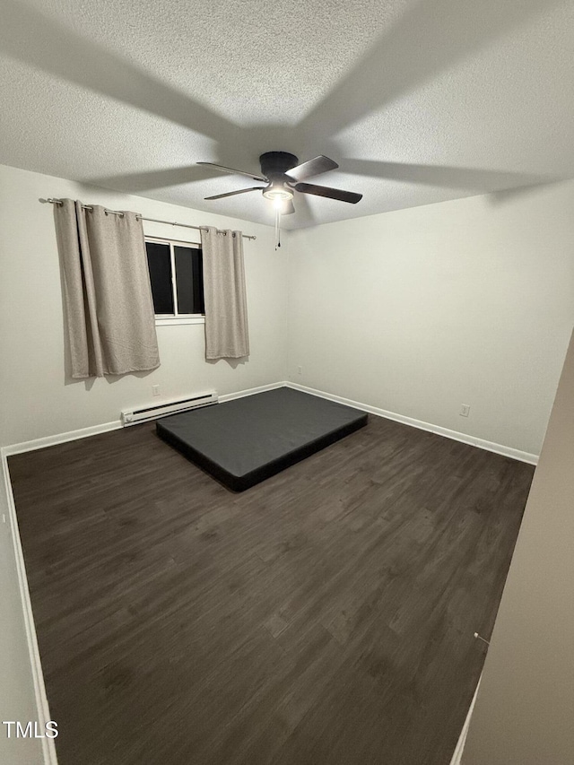 unfurnished room with ceiling fan, dark wood-type flooring, a textured ceiling, and baseboard heating