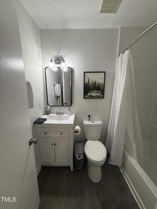 full bathroom with vanity, wood-type flooring, a textured ceiling, toilet, and shower / bath combo with shower curtain