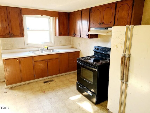 kitchen with tasteful backsplash, sink, black electric range, and white refrigerator