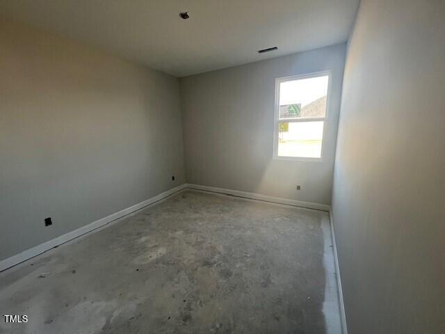 spare room with visible vents, baseboards, and unfinished concrete flooring