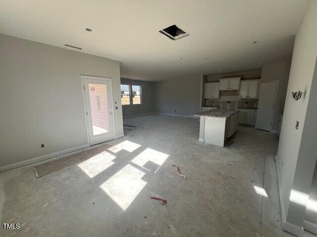 kitchen featuring a center island, open floor plan, white cabinetry, and baseboards