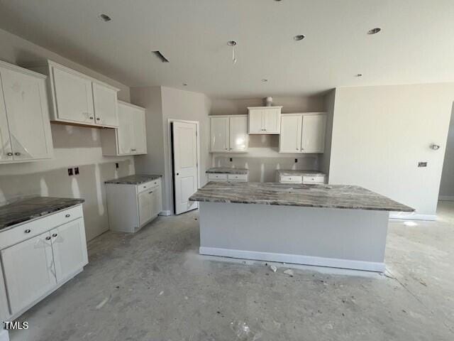 kitchen with white cabinetry, concrete flooring, and a center island