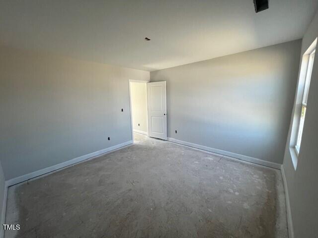 spare room featuring unfinished concrete flooring and baseboards