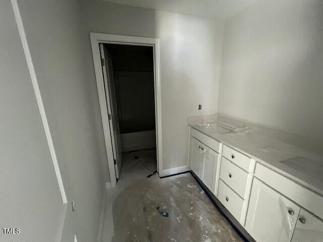 bathroom with unfinished concrete flooring, vanity, and baseboards