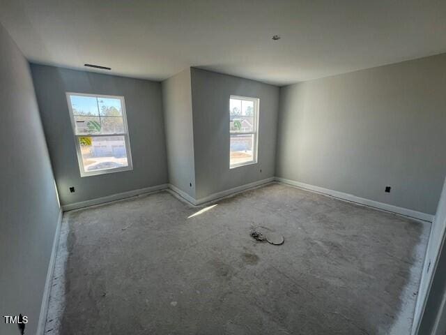 empty room with visible vents, a wealth of natural light, and baseboards