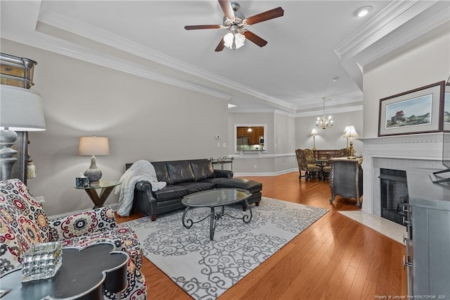 living room featuring crown molding, ceiling fan with notable chandelier, and light wood-type flooring