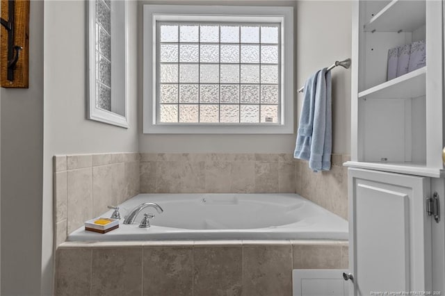 bathroom with a relaxing tiled tub and a healthy amount of sunlight