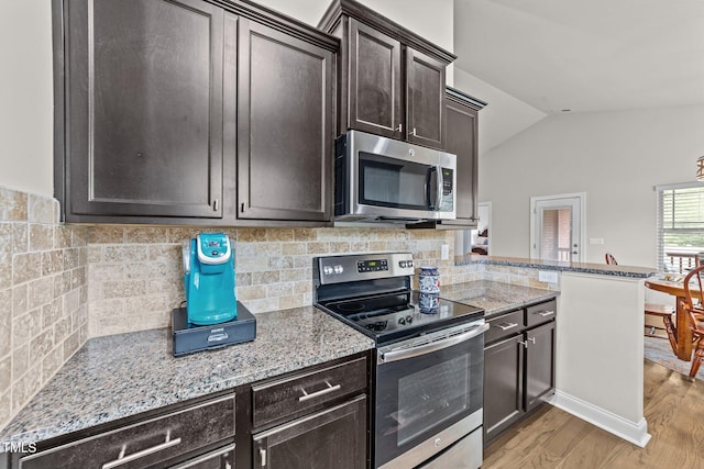 2001 Bunnfield Dr, Zebulon, NC 27597 - kitchen featuring appliances with stainless steel finishes, lofted ceiling, light stone countertops, light wood-style floors, and decorative backsplash