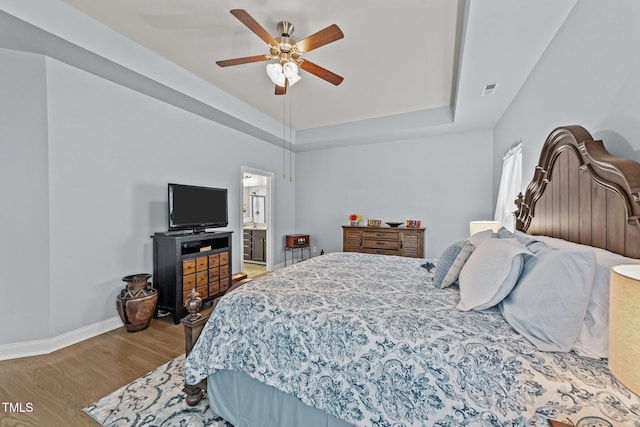 2001 Bunnfield Dr, Zebulon, NC 27597 - bedroom with wood finished floors, a raised ceiling, a ceiling fan, and ensuite bath