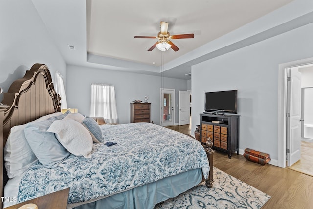 2001 Bunnfield Dr, Zebulon, NC 27597 - bedroom with wood finished floors, a raised ceiling, a ceiling fan, and ensuite bathroom