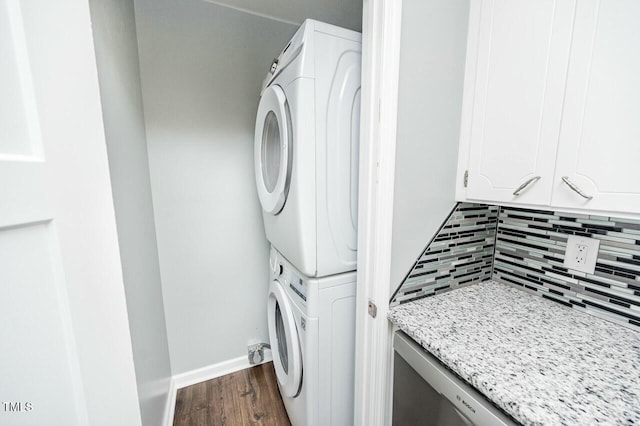 laundry area featuring dark wood-type flooring and stacked washing maching and dryer