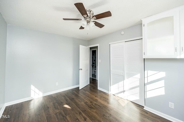 unfurnished bedroom with dark hardwood / wood-style floors, ceiling fan, and a closet