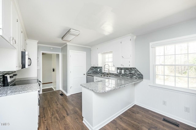 kitchen featuring sink, dark wood-type flooring, stainless steel appliances, white cabinets, and kitchen peninsula