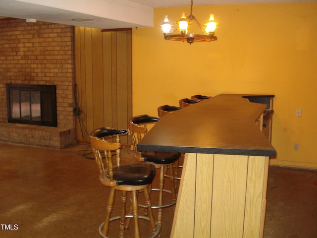 bar with a brick fireplace, decorative light fixtures, and light brown cabinets